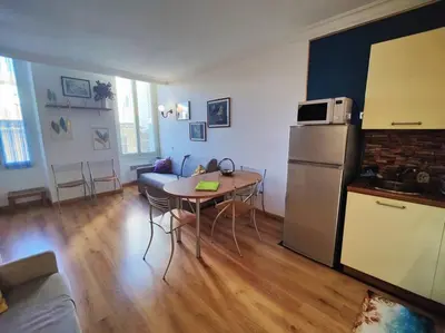 a kitchen and a living room with a table and a refrigerator at Central close to beaches and shops, up till 6 pers in Nice
