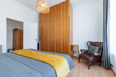 a bedroom with a bed with a yellow blanket and a chair at The place to be in Nice in Nice