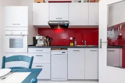 a kitchen with white cabinets and a red wall at The place to be in Nice in Nice