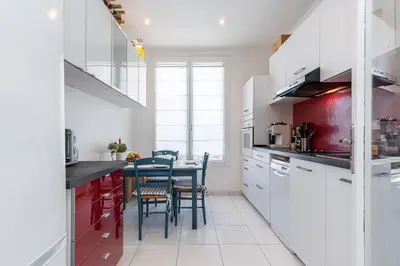 a kitchen with white cabinets and a table with chairs at The place to be in Nice in Nice
