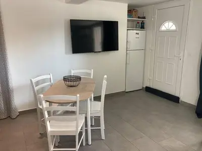 a dining room with a table and chairs and a television at Superbe appartement au calme et vue sur la mer in Cagnes-sur-Mer
