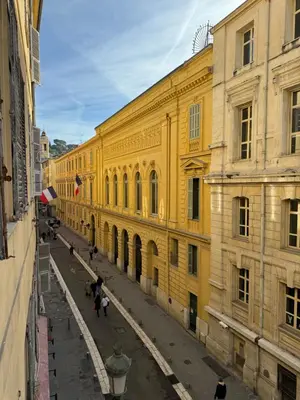 a yellow building with people walking in a street at Duplex spagiari in Nice