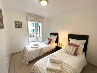 two beds in a room with a window at Sunlight Properties - Mirage - Central Nice with Parking and Terrace in Nice
