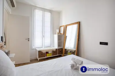 a white bedroom with a bed and a mirror at Apartment T2 Air-conditioned district Libération in Nice