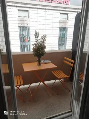 a table and chairs on a balcony with a vase of flowers at Nice Charmant 2 pièces in Nice