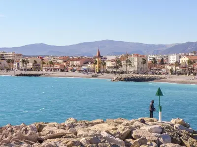 a person standing on the rocks near the water at Apartment Rive de Cagnes by Interhome in Cagnes-sur-Mer