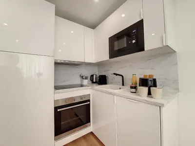 a white kitchen with white cabinets and a microwave at Nestor&Jeeves - COEUR RIVIERA - City Center - Near Beach in Nice