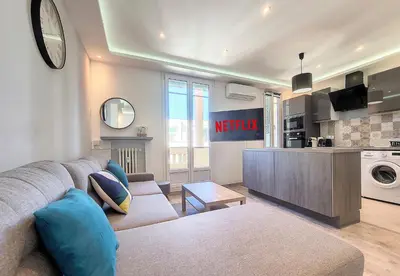 a living room with a couch and a kitchen at Nestor&Jeeves - PALAIS HISPANIA - Top floor apartment in Nice