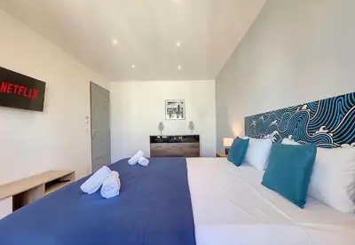 a bedroom with a large bed with blue and white pillows at Nestor&Jeeves - PALAIS HISPANIA - Top floor apartment in Nice
