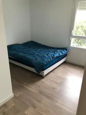 a bed in a room with a wooden floor at Logement neuf proche plage et aéroport in Nice