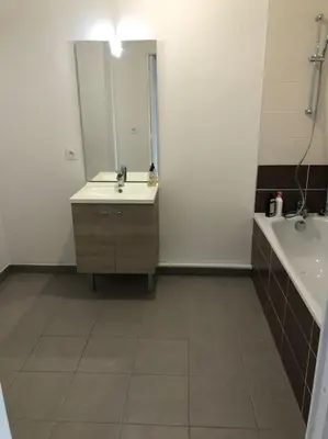 a bathroom with a sink and a tub and a mirror at Logement neuf proche plage et aéroport in Nice