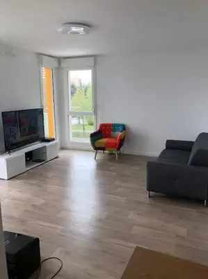 a living room with a couch and a television at Logement neuf proche plage et aéroport in Nice