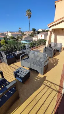 a row of lounge chairs on a patio with a palm tree at Les studios des mandariniers in Cagnes-sur-Mer