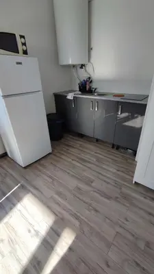 a kitchen with a white refrigerator and a wooden floor at Les studios des mandariniers in Cagnes-sur-Mer