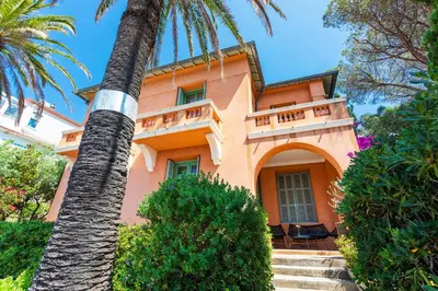 a palm tree in front of a pink house at Villa Reve d azur vi4353 by Riviera Holiday Homes in Nice