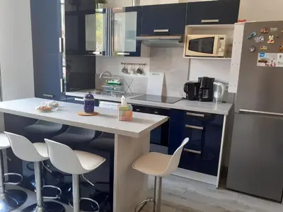 a kitchen with blue cabinets and white counters and stools at 2 Pièces Neuf WIFI Quartier Borriglione in Nice