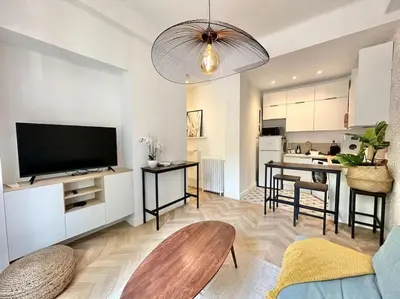a living room with a television and a kitchen at Magnifique appartement moderne - Clim & Wifi in Nice