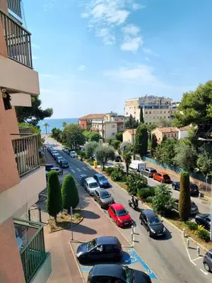 a city street with cars parked in a parking lot at Rose Garden in Cagnes-sur-Mer