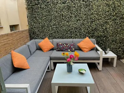 a blue couch with orange pillows and a table with flowers at La Maison Hélène & Antoine Nice Le Port in Nice