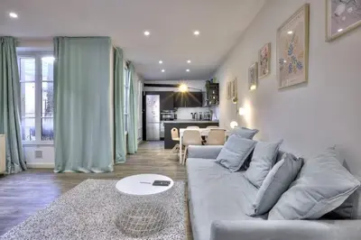 a living room with a gray couch and a kitchen at La Maison Hélène & Antoine Nice Le Port in Nice