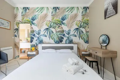 a bedroom with a bed with a tropical wallpaper at VILLA CRUG HYWEL - VILLEFRANCHE-SUR-MER in Villefranche-sur-Mer