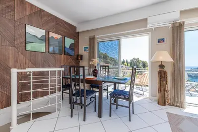 a dining room with a table and chairs and a balcony at VILLA CRUG HYWEL - VILLEFRANCHE-SUR-MER in Villefranche-sur-Mer