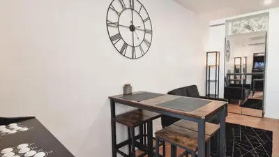 a dining room with a table and a clock on the wall at Loft Place Massena in Nice