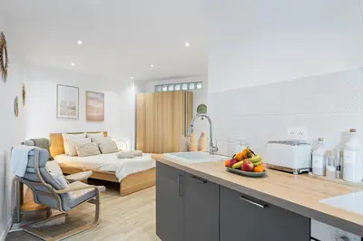 a kitchen and living room with a bed in the background at Appartement bord de mer « La Petite Ma-Line » in Cagnes-sur-Mer