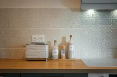a kitchen counter with a toaster and bottles of wine at Appartement bord de mer « La Petite Ma-Line » in Cagnes-sur-Mer