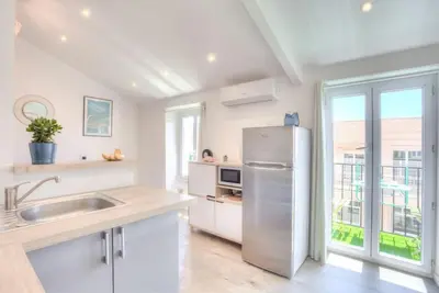 a white kitchen with a stainless steel refrigerator at #2 Central Studio top floor AC & Balcony in Nice