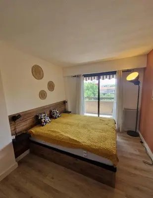 a bedroom with a bed and a large window at Cagnes sur Mer-Spacieux 2 pièces in Cagnes-sur-Mer