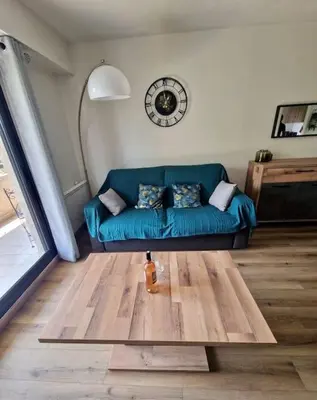 a living room with a blue couch and a clock at Cagnes sur Mer-Spacieux 2 pièces in Cagnes-sur-Mer
