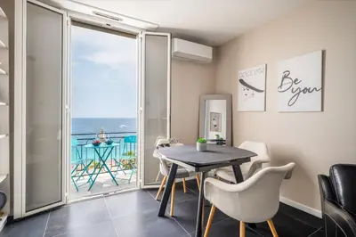 a dining room with a table and a view of the ocean at Le balcon de la baie des Anges in Nice