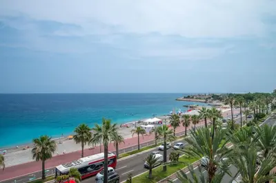 a view of a beach with palm trees and a bus at Le balcon de la baie des Anges in Nice