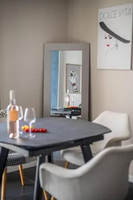 a dining room with a table and chairs and a mirror at Le balcon de la baie des Anges in Nice