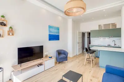 a living room with a large television and a blue couch at #43 Design Studio Terrace AC Wifi Sea View 1min Beach in Nice