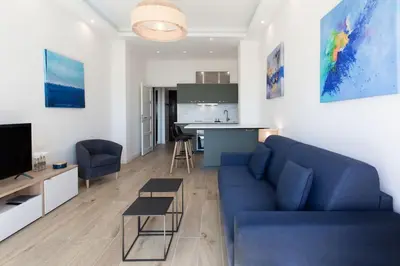 a living room with a blue couch and a kitchen at #43 Design Studio Terrace AC Wifi Sea View 1min Beach in Nice
