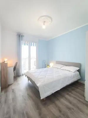 a white bedroom with a large bed and a desk at F4 avec vue mer / Flat with sea view 3 bedrooms in Nice