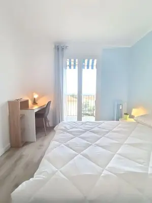 a white bedroom with a large bed and a desk at F4 avec vue mer / Flat with sea view 3 bedrooms in Nice