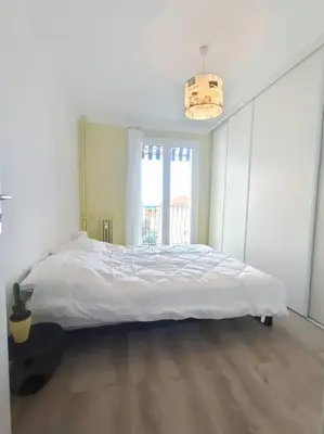 a bedroom with a large white bed with a window at F4 avec vue mer / Flat with sea view 3 bedrooms in Nice