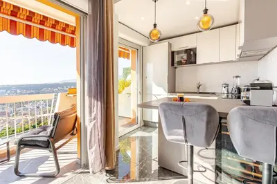 a kitchen with a table and chairs and a balcony at Vue mer et montagne panoramique in Nice