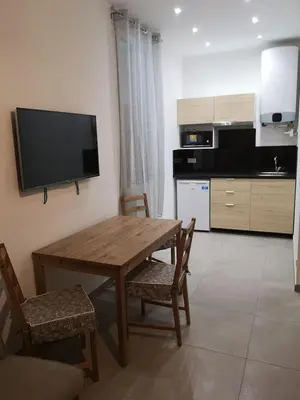 a kitchen with a wooden table and chairs and a television at maison de papa in Nice