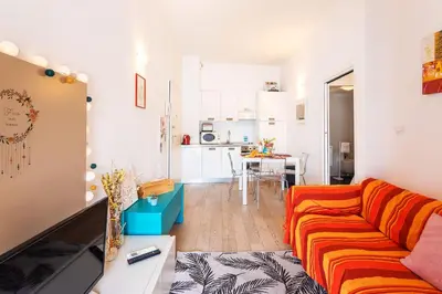 a living room with a orange couch and a kitchen at LA RESERVE AP4369 By Riviera Holiday Homes in Villefranche-sur-Mer