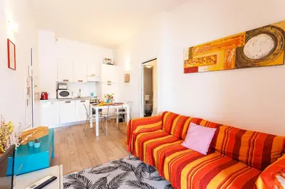 a living room with a orange couch and a kitchen at LA RESERVE AP4369 By Riviera Holiday Homes in Villefranche-sur-Mer