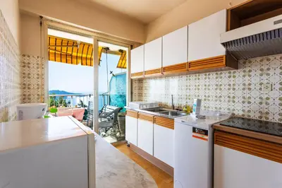 a kitchen with white cabinets and a large window at LE CALIFORNIA 3 AP4366 By Riviera Holiday Homes in Villefranche-sur-Mer