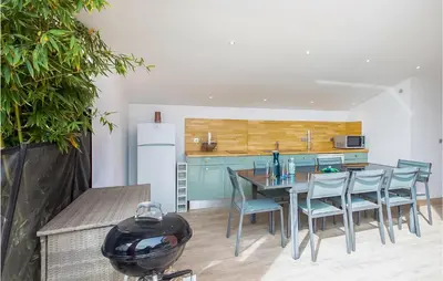 a kitchen with a table and chairs and a refrigerator at Nice Home In Saint-Laurent-Du-Var in Saint-Laurent-du-Var