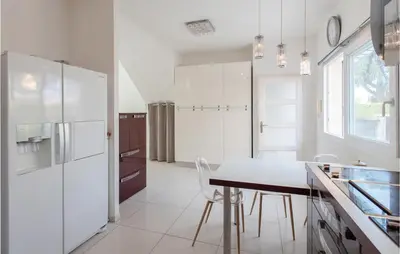 a white kitchen with a table and a refrigerator at Nice Home In Saint-Laurent-Du-Var in Saint-Laurent-du-Var
