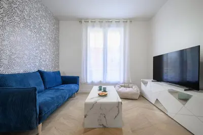 a bed with a blue wall with a clock on it at Le Walesa, magnifique 3P, spacieux et rénové, Port de Nice in Nice