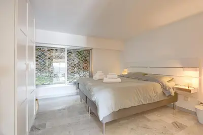 a white bedroom with a bed and a window at Giant Terrace on a stunning View in Villefranche-sur-Mer