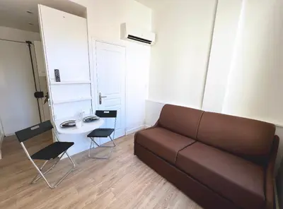 a living room with a couch and a table and chairs at Cosy studio ensoleillé - centre-ville – TRAM/AC in Nice